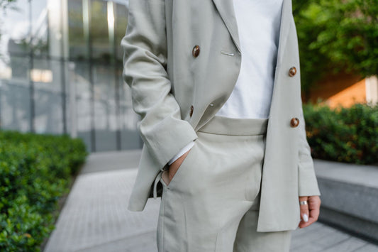 Close-up of a soft sage linen blazer and trousers worn with a white shirt outdoors